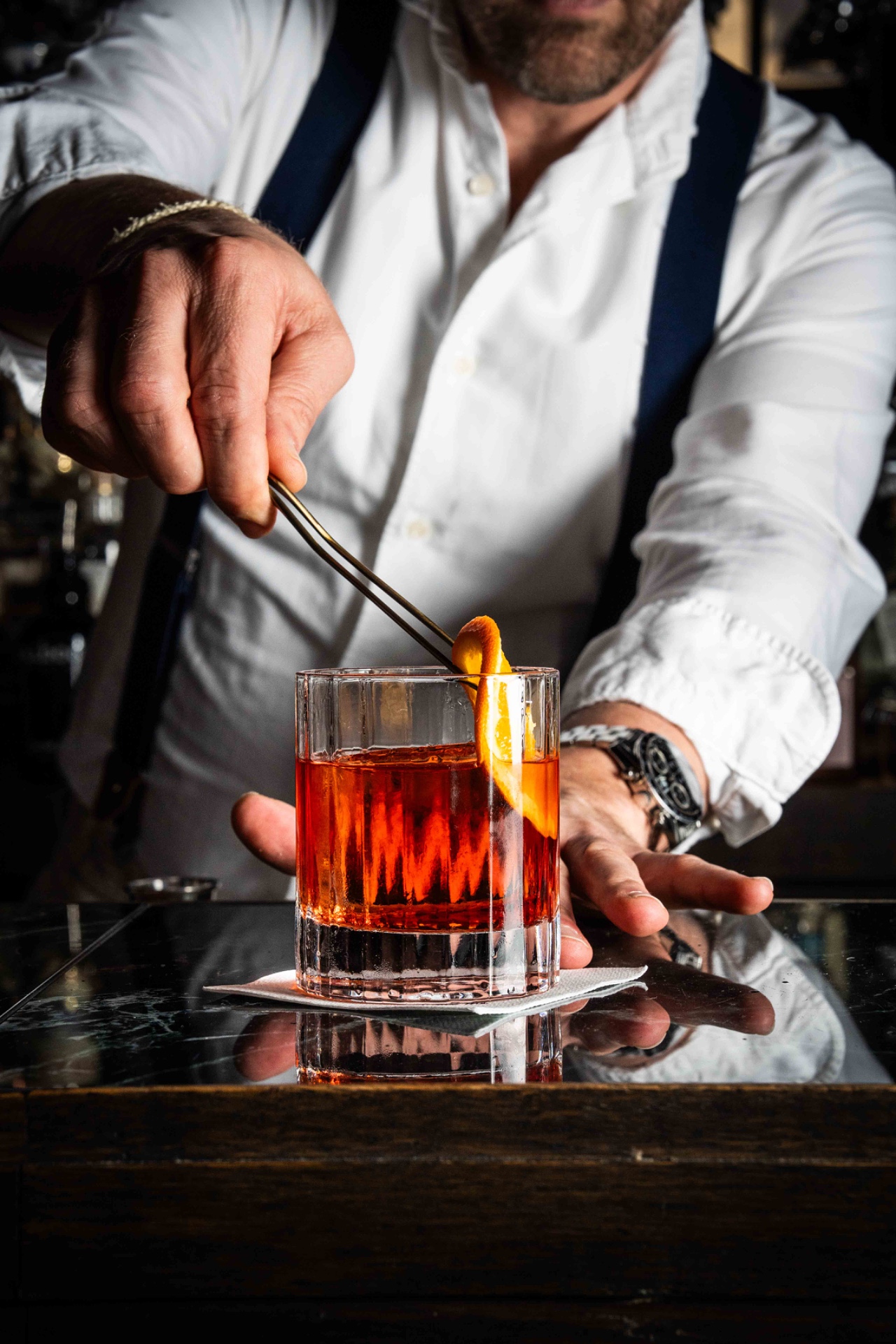 Bartender legt een sinaasappelzeste op een negroni