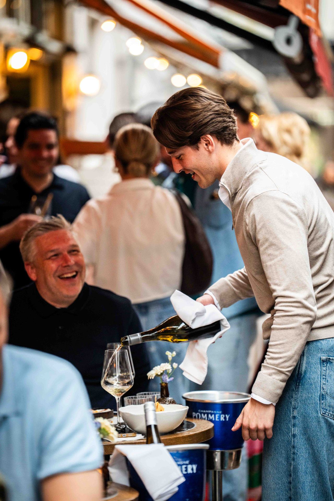 Gastheer schenkt wijn bij op een gezellig terras