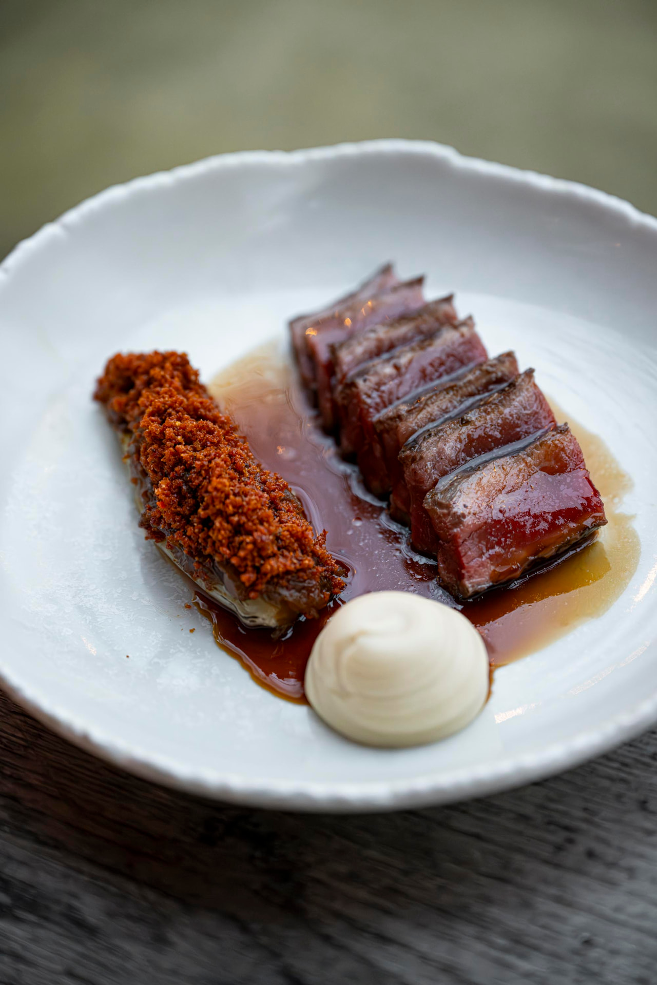 Gelakt vlees met krokante crumble en room op een wit bord
