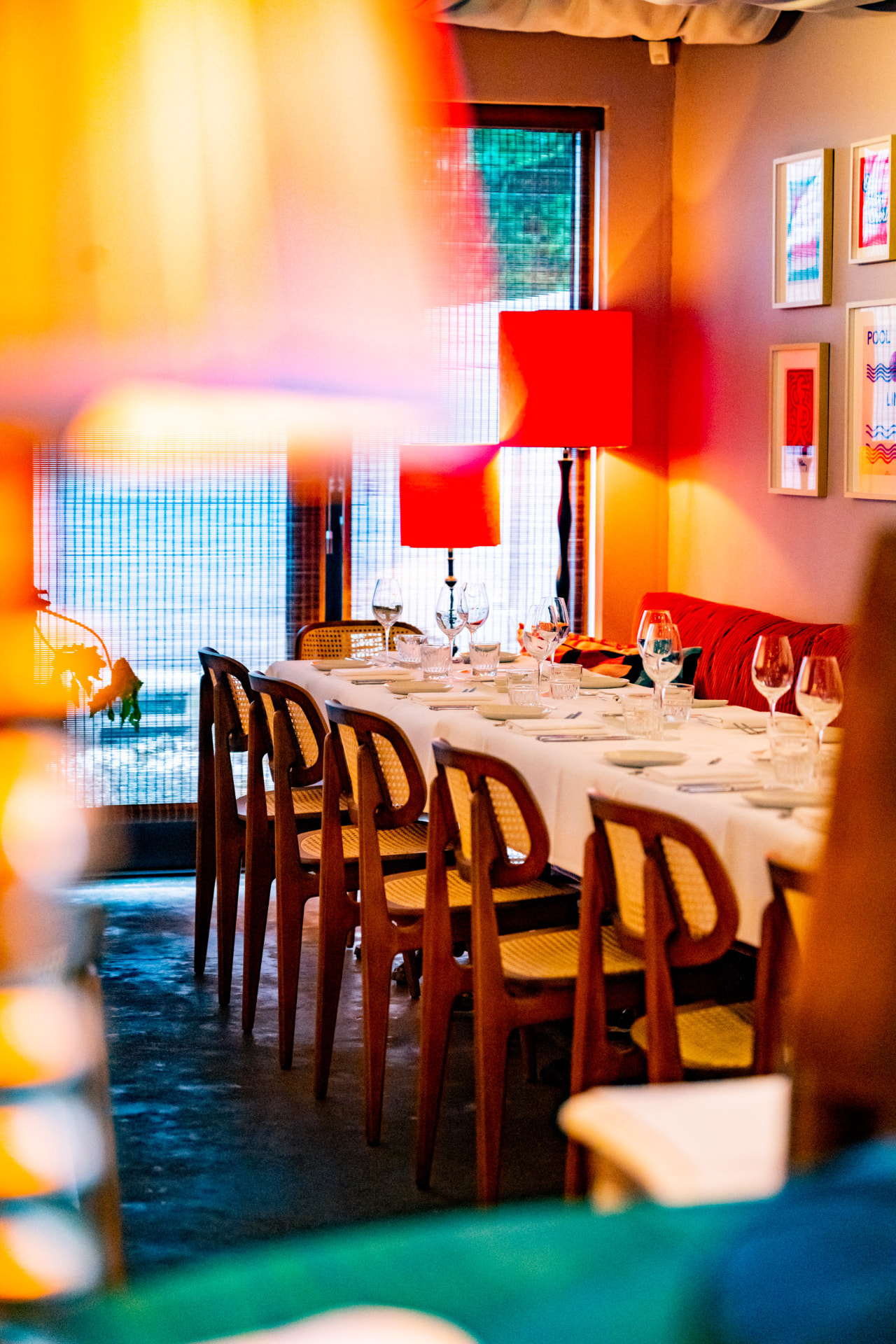 Kleurrijke eetzaal met rode lampen en een lange gedekte tafel