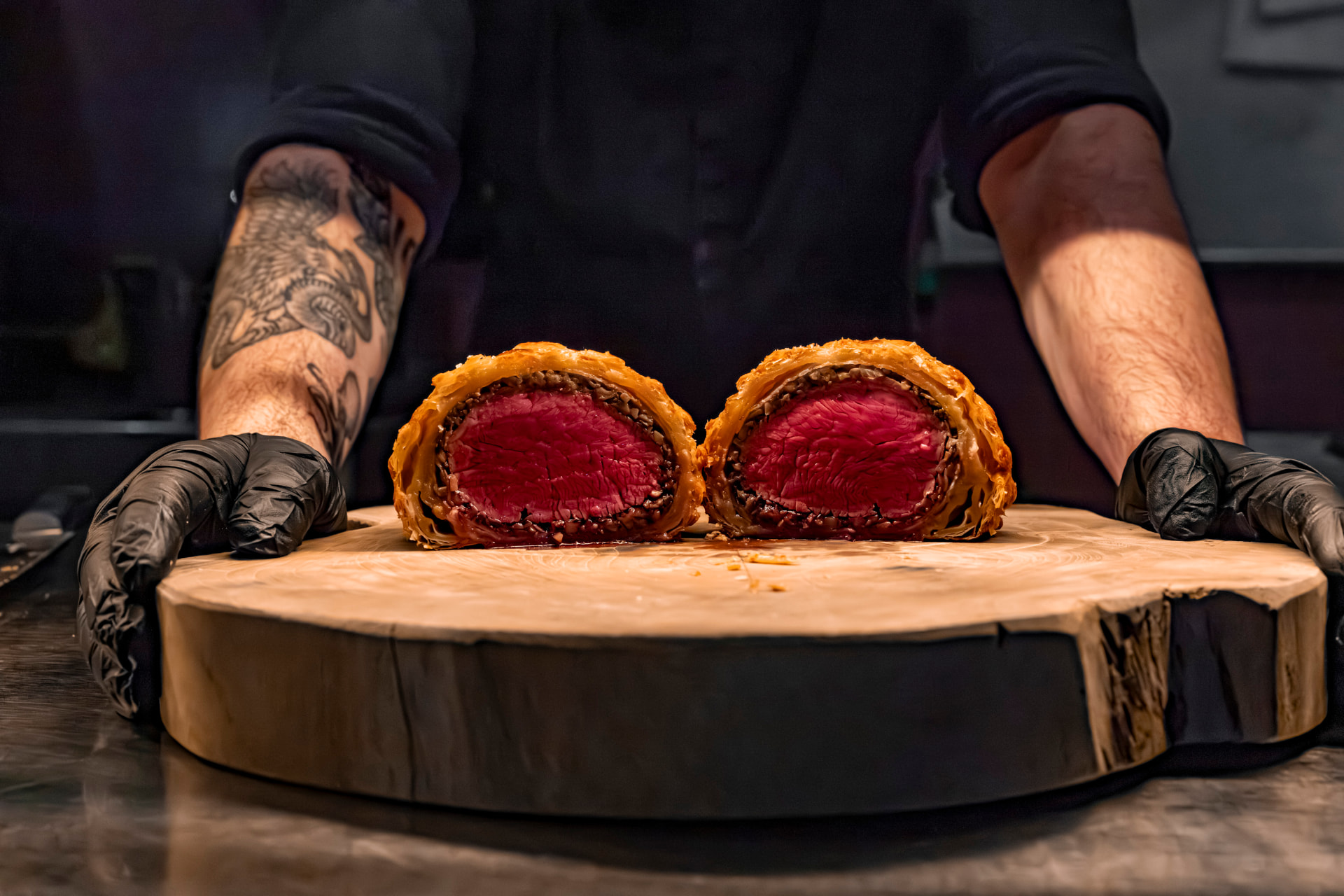 Chef presenteert een aangesneden wellington op een houten plank