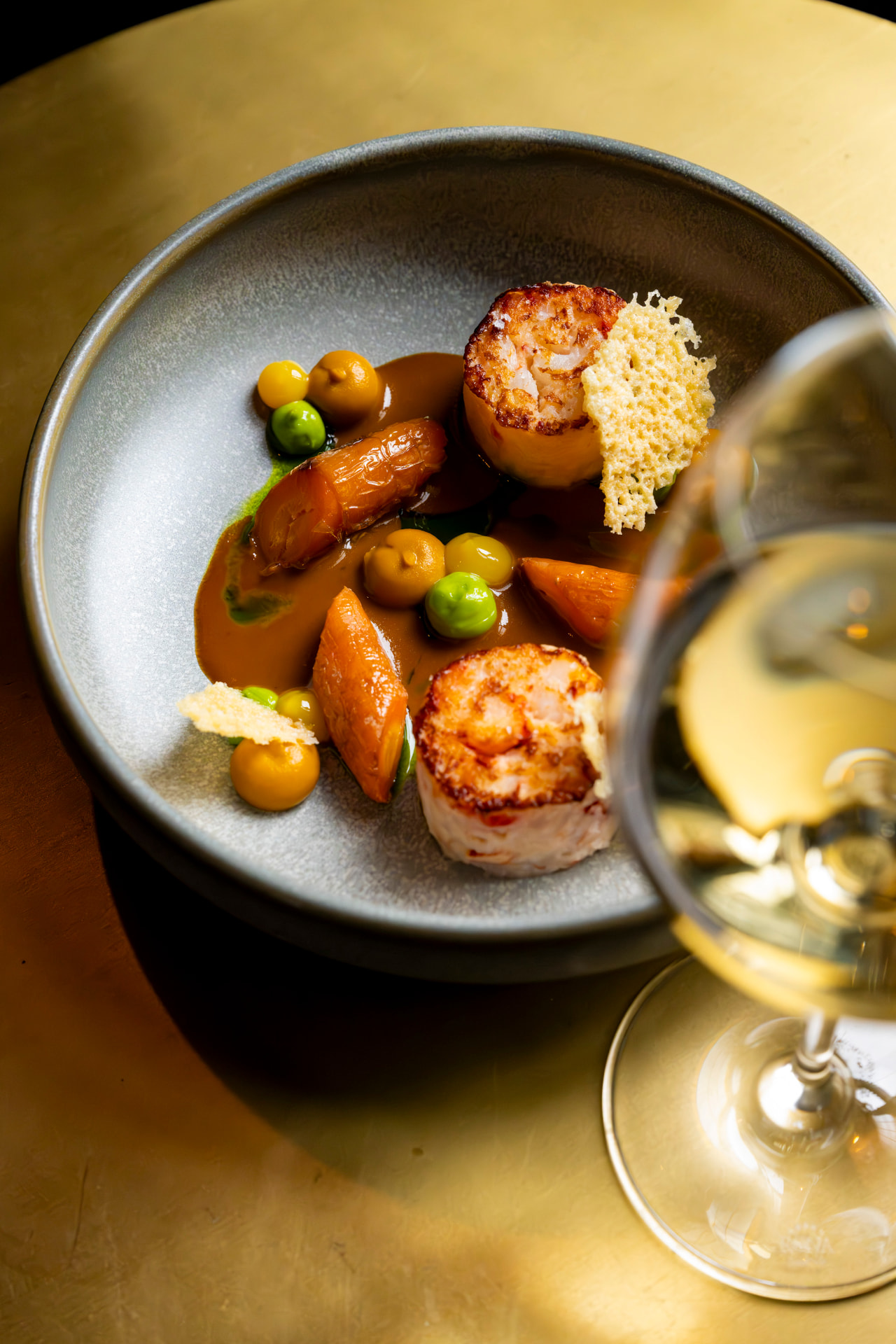 Langoustine met wortel en jus op een gouden tafel